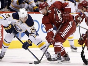 Buffalo Sabres' Mikhail Grigorenko (25), of Russia, battles Arizona Coyotes' Sam Gagner (9) for the puck after a face-off during the first period of an NHL hockey game Monday, March 30, 2015, in Glendale, Ariz. (AP Photo/Ross D. Franklin)