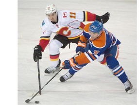 Taylor Hall of the Edmonton Oilers reaches for the puck in front of the Calgary Flames’ Mikael Backlund during Saturday’s National Hockey League game at Rexall Place.