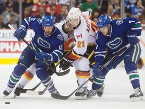 Vancouver Canucks’ Brad Richardson (15) and Linden Vey (7) battle for the puck with Calgary Flames’ Mason Raymond (21) during the first period of an NHL hockey game in Vancouver, B.C., on Saturday December 20, 2014.