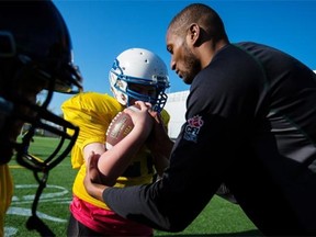 Adarius Bowman of the Edmonton Eskimos works with players to improve their form during the Eskimos’ amateur football camp at Clarke Field on Monday.