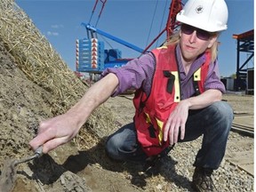 Archeologist Ryan Eldridge scrapes back the dirt at the site of a fur trade-era garbage pit he found during construction for the new Walterdale Bridge.