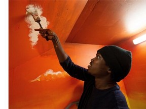 Artist Andrew Jackson Obel puts the finishing touches on a mural in the stairwell at International House on March 4, 2015 in Edmonton.