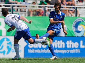 FC Edmonton midfielder Chad Burt, left, gets in front of a kick by New York Cosmos forward Raul during NASL action May 10, 2015, at Shuart Stadium in Hempstead, N.Y.