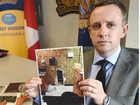 Edmonton police Det. Rae Gerrard of the criminal investigations section holds a photo of the hole in the wall the thieves used in a jewelry heist at Paris Jewellers in Edmonton, April 24, 2015.