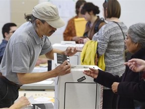An election official explains to a voter how to mark the ballot in the provincial election at the polling station in Ritchie Community Hall in Edmonton on Tuesday May 5, 2015.