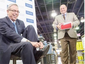 Federal Finance Minister Joe Oliver tries on his new budget shoes with the assistance of Bruce Dinan, president of Town Shoes, during a photo op in Toronto on April 20, 2015.