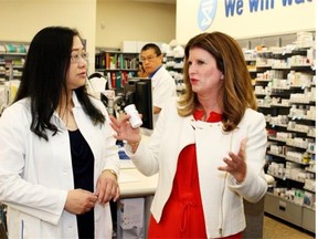 Federal Health Minister Rona Ambrose (right) discusses prescription drugs with Shoppers Drug Mart pharmacist-owner Camilla Fung (left) in Edmonton on May 19, 2015. Ambrose was hosting a symposium with stakeholders on the prescription drug abuse in Alberta.