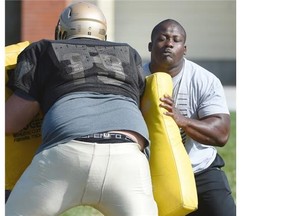 Edmonton Eskimos defensive lineman Almondo Sewell uses a pad to block players during a drill at the Edmonton Huskies’ spring camp at Kinsmen Park on May 10, 2015.