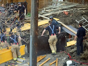 Firefighters try to recover a worker who was buried alive under dirt and clay when a trench collapsed at 108th Avenue and 123rd Street in Edmonton on April 28, 2015.
