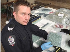 Sgt. Steve Sharpe poses with a bag of fentanyl pills at police headquarters on Friday, May 1. Seven people are facing more than 150 drug and firearm-related charges in connection with four investigations, which saw Edmonton police seize drugs, guns and stolen property.
