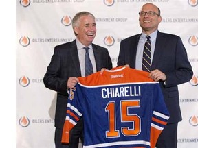 Edmonton Oilers CEO Bob Nicholson (left) and new president and general manager Peter Chiarelli (right) hold up an Oilers jersey with Chiarelli's name after he joined the team on April 24, 2015.
