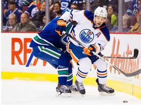 Taylor Hall of the Edmonton Oilers slips away from Vancouver Canucks defenceman Christopher Tanev in an NHL game at Rogers Arena in Vancouver on April 11, 2015.