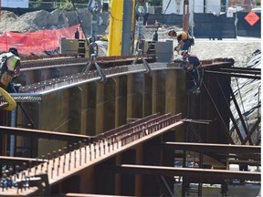 Workers reinstall girders at the 102 Ave Bridge over Groat Road
