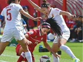 Canada’s Jonelle Filigno is caught in a tough position by China’s Wu Haiyan (5) and Wang Lisi during the Women’s World Cup opening game at Commonwealth Stadium on June 6, 2015.