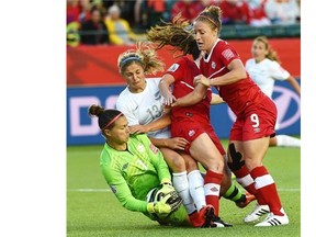 Canada’s Josee Belanger (9), Allysha Chapman (15) and New Zealand’s Rosie White (13) crash into goalkeeper Erin McLeod (1) as she makes a save late in the match during the FIFA Women’s World Cup at Commonwealth Stadium in Edmonton on June 11, 2015.