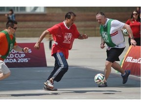 Councillor Amarjeet Sohi of the "City Hall Slickers" battles for the ball between Javier Salazar and Garrett Turta during the Soccer Showdown behind the Stanley Milner Library in Edmonton on May 26, 2015.