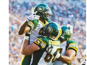 Edmonton Eskimos' Adarius Bowman, left, celebrates with teammates Matthew O'Donnell, centre, and D'Anthony Baptiste after scoring a touchdown against the Montreal Alouettes during first half CFL football action in Montreal, Friday, August 8, 2014. THE CANADIAN PRESS/Graham Hughes
