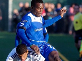FC Edmonton’s Lance Laing runs over Ethen Sampson of the Vancouver Whitecaps during an Amway Canadian Championship semifinal game at Clarke Field on May 20, 2015.