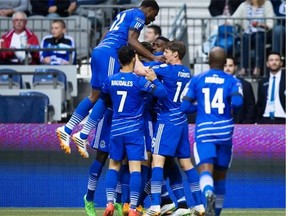 FC Edmonton’s Tomi Ameobi is mobbed by his teammates after scoring against the Vancouver Whitecaps during the first half of a Canadian Championship semifinal soccer game in Vancouver on May 13, 2015.