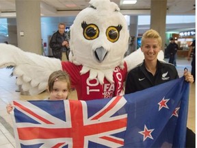 Four-year-old Kate Straka and Football Ferns captain Abby Erceg hold up the New Zealand flag while Shueme, the FIFA Women’s World Cup mascot, spreads her wings in the background at Edmonton International Airport on Tuesday.