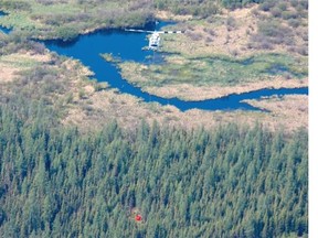 A helicopter drags a water bucket between a water source and a contained wildfire approximately 22 kilometres east of Slave Lake Alta. on May 27, 2015.