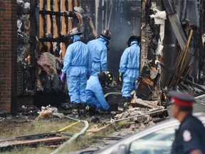 Investigators look over the scene of the burned-out house at 18620-62A Ave. where a police officer was killed while trying to serve a warrant on Monday. Const. Daniel Woodall is the first Edmonton Police Service officer killed in the line of duty in 25 years.