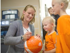 Mandy van den Berg of the Netherlands women’s soccer team autographs a soccer ball after arriving at the Edmonton International Airport on Monday.