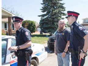 Neighbour Ryan Colton, centre, speaks with officers on Tuesday June 9, 2015 at the scene where Cst. Dan Woodall was shot and killed overnight in Edmonton, Alberta. Colton witnessed the entirety of the incident. THE CANADIAN PRESS/Amber Bracken