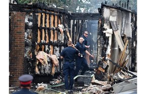 Police officers investigate at the scene of the burned out house at 18620-62A Ave. where Const. Daniel Woodall was killed while trying to serve a warrant on Monday.