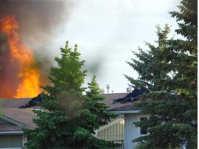 Police surround a burning house following a shooting near 186 St. and 62A Ave. in Edmonton on June 8, 2015.