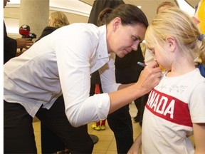 Team captain Christine Sinclair signs a shirt belonging to Sophie Hendricks, 6, at the Edmonton International Airport on June 2, 2015, as Canada’s national women’s soccer team arrives to take part in the FIFA Women’s World Cup.