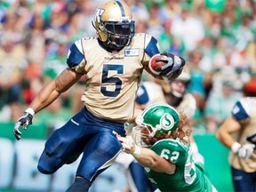 Winnipeg Blue Bombers running back Chad Simpson, left, breaks a tackle from Saskatchewan Roughriders defensive lineman Levi Steinhauer during the first half of CFL football action in Regina on September 1, 2013.