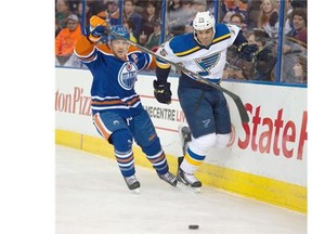 Andrew Ference of the Edmonton Oilers, left, chases a loose puck with Ryan Reaves of the St. Louis Blues at Rexall Place on Saturday, Feb. 28, 2015.