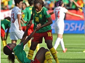 Cameroon’s Henriette Akaba (18) helps up a dejected Jeannette Yango (10) after being defeated by China 1-0 during round of 16 play at the FIFA Women’s World Cup at Commonwealth Stadium on Saturday, June 20, 2015.