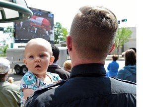 Colin Sinclaire and his daughter Isla, 10 months, watch Const. Daniel Woodall’s funeral on a big screen in front of the Shaw Conference Centre on Jasper Avenue on Wednesday June 17, 2015.