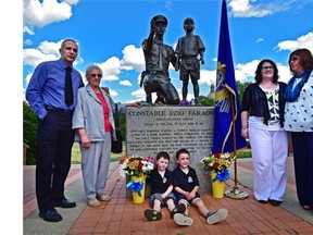 Family and friends gathered to remember Ezio Faraone, a police constable killed while pursuing a bank robber 25 years ago in Edmonton, during a ceremony to mark the 25th anniversary of his his death. Faraone's brother Paul (L), mother Elsa (2nd left), sister Joanne (far right) and Claire Woodall with sons Gabe and Callen, pose beside a statue of Faraone at Ezio Faraone Park, June 25, 2015. Woodall's husband, Const. Daniel Woodall. was killed about three weeks ago in the line of duty.