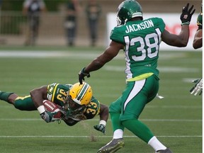 Edmonton Eskimos’ Shakir Bell (33) is tripped up by Tristan Jackson (38) of the Saskatchewan Roughriders during pre-season Canadian Football League action in Fort McMurray on June 13, 2015.