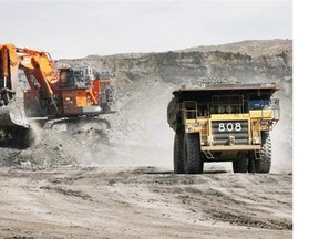 A haul truck carrying a full load drives away from a mining shovel at the Shell Albian Sands oilsands mine near Fort McMurray, Alta., Wednesday, July 9, 2008.
