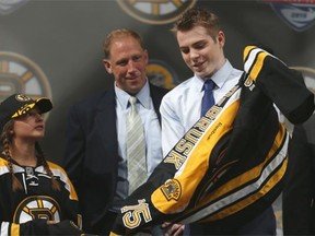 Jake DeBrusk puts on a Boston Bruins jersey after being picked 14th overall in the 2015 NHL entry draft.