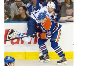 Justin Schultz of the Edmonton Oilers checks Leo Komarov of the Toronto Maple Leafs into the boards during an NHL game at Rexall Place on March 16, 2015.