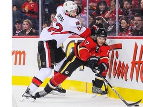 Lance Bouma (#17) of the Calgary Flames reaches for the puck as Eric Gryba (#62) of the Ottawa Senators looks to check him during an NHL game at Scotiabank Saddledome in 2014. The Senators traded Gryba to the Oilers in a deal Saturday.