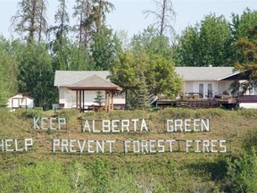 A large sign reminding citizens to help prevent forest fires looms over the town of Athabasca on May 26, 2015.