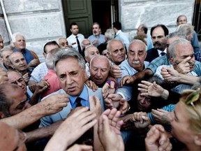 The manager of a national bank branch delivers priority numbers to pensioners, as banks only opened for the retired to allow them to cash up to 120 euros in Athens on July 1, 2015. The European Union will decide whether to grant Greece a last-minute bailout package to avoid pushing it further towards an exit from the eurozone.