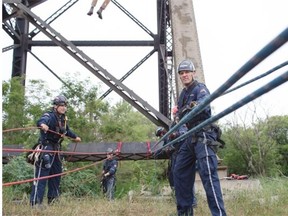 Members of the Edmonton Fire Rescue Services Technical Rescue work together during a specialized training exercise on the pillars of the High Level Bridge in Edmonton on June 30, 2015.