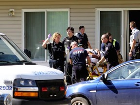 Emergency officials wheel a patient from an apartment in Grande Prairie, Alta., following a shooting on Saturday, June 27, 2015.