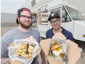 Northlands’ food truck Truck 1879 chef Parker Regimbald, left, and food truck manager Tony Mah display a Korean pulled pork burger with fried egg and duck fat kennebec garlic fries drizzled with Béarnaise sauce.