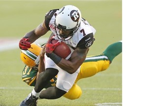 Ottawa RedBlacks Maurice Price is tackled by Edmonton Eskimos Calvin McCarty during Canadian Football League game action in Edmonton on July 9, 2015.