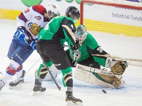 Prince Albert Raiders goaltender Cole Cheveldave, right, makes a save while Brendan Guhle, centre, ties up Edmonton’s Mitchell Moroz during game one of the first round of playoffs at Rexall Place in Edmonton on March 22, 2014.
