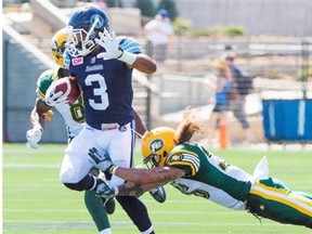Toronto Argonauts running back Brandon Whitaker sidesteps an attempted tackle by Edmonton Eskimos defensive back Aaron Grymes during a Canadian Football League game at Fort McMurray on June 27, 2015.