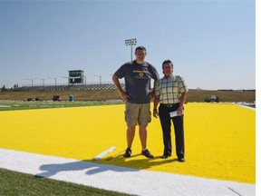 University of Alberta Golden Bears football head coach Chris Morris, left, and Cheryl Harwardt, director of operations for the faculty of physical education and recreation, stand on the new turf at Foote Field on July 9, 2015.